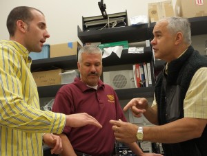 Lee Schoen, left, explains to Donald Uzarski, center, and Jim Student how he makes thin slices of fish ear bones. Photo: Leslie Mertz.