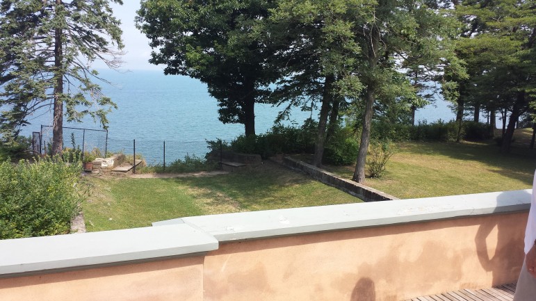 A wide porch overlooks the lawn connecting the home to a cliff high above Lake Erie.