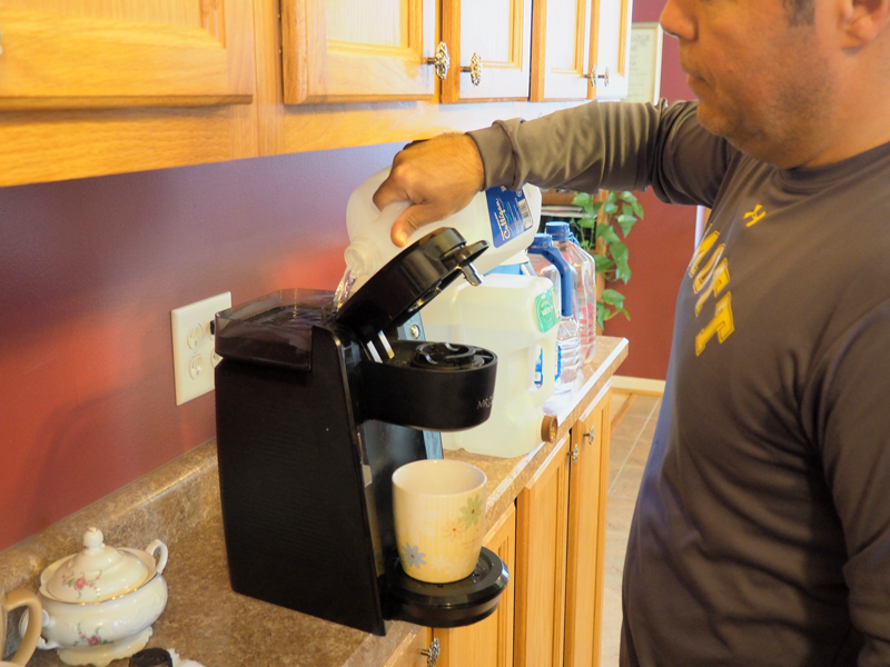 Angel Garcia pours water from the National Guard into his coffee maker. Image: Amanda Proscia