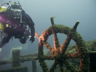 A diver investigates the wheel from the schooner FT Barney. Image: Joe Hoyt/NOAA, Thunder Bay National Marine Sanctuary 