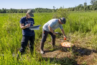  Student researchers Ava Whitlock and Brody Glei get ready to fly a drone equipped with a heat-sensitive camera to find rare eastern massasauga rattlesnakes. Image: Ruth Thorton/WKAR