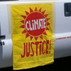 A climate justice banner hanging from the side of a vehicle