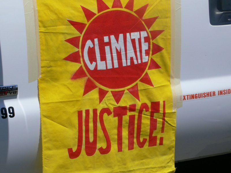 A climate justice banner hanging from the side of a vehicle