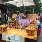 2 children sitting on a bench together with crowns and sashes after winning a competition