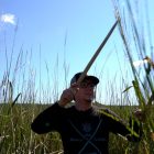 Man holding a "knocking stick," a tool used to harvest manoomin.
