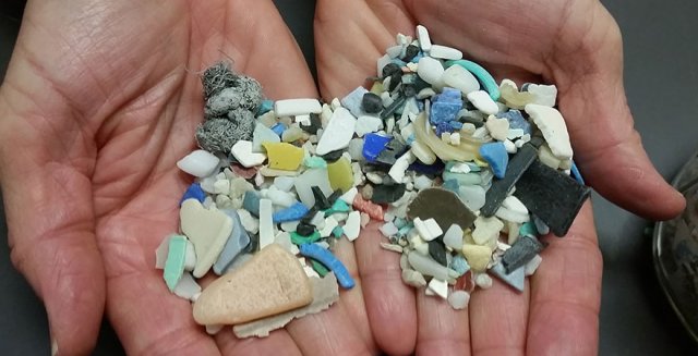 Pieces of microplastic in two outstretched hands.