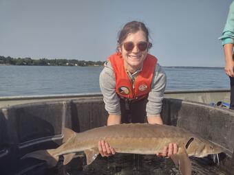 Holly Embke holds a sturgeon while in a boat.