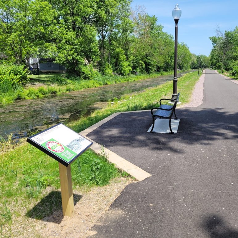 A small sign along a paved trail