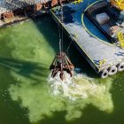 Machines drop limestone into the lake.