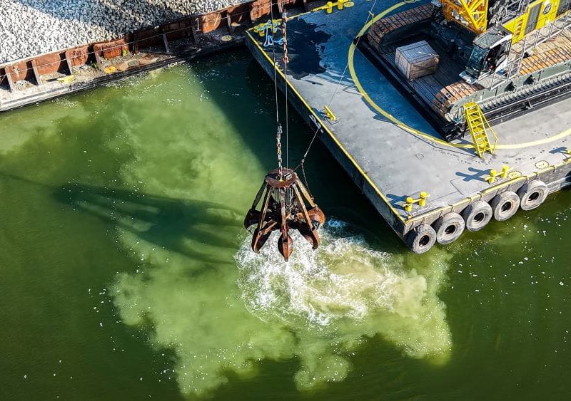 Machines drop limestone into the lake.