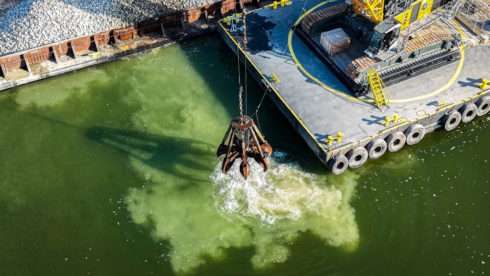 Machines drop limestone into the lake.