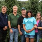 Wahmoff Farms family members stand in front of evergreen trees.