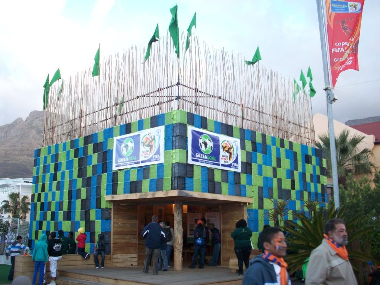 A building with green, blue and black checkered squares. Banners advertising the World Cup adorn the building.